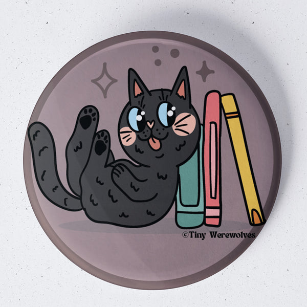 Based in Chicago by queer artist & designer Kayla Pekkala - Tiny Werewolves | Black Book Cat 1.75" Button Pin in | Shop to get your Metal Pinback Button with collections featuring retro-inspired designs infused with social commentary art, highlighting modern social & current events.