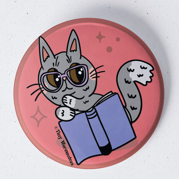 Based in Chicago by queer artist & designer Kayla Pekkala - Tiny Werewolves | Grey Book Cat 1.75" Button Pin in | Shop to get your Metal Pinback Button with collections featuring retro-inspired designs infused with social commentary art, highlighting modern social & current events.