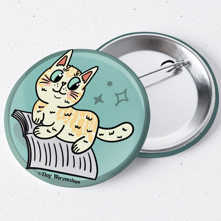 Based in Chicago by queer artist & designer Kayla Pekkala - Tiny Werewolves | Orange Book Cat 1.75" Button Pin in | Shop to get your Metal Pinback Button with collections featuring retro-inspired designs infused with social commentary art, highlighting modern social & current events.