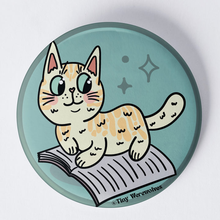 Based in Chicago by queer artist & designer Kayla Pekkala - Tiny Werewolves | Orange Book Cat 1.75" Button Pin in | Shop to get your Metal Pinback Button with collections featuring retro-inspired designs infused with social commentary art, highlighting modern social & current events.