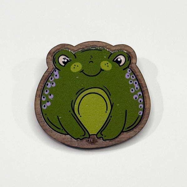 Based in Chicago by queer artist & designer Kayla Pekkala - Tiny Werewolves | Frog Wood Pin in Walnut | Shop to get your Wood Pin with collections featuring retro-inspired designs infused with social commentary art, highlighting modern social & current events.