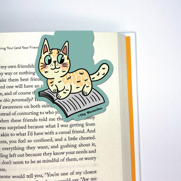 Based in Chicago by queer artist & designer Kayla Pekkala - Tiny Werewolves | Orange Book Cat Laminated Magnetic Bookmark in | Shop to get your Magnetic Bookmark with collections featuring retro-inspired designs infused with social commentary art, highlighting modern social & current events.