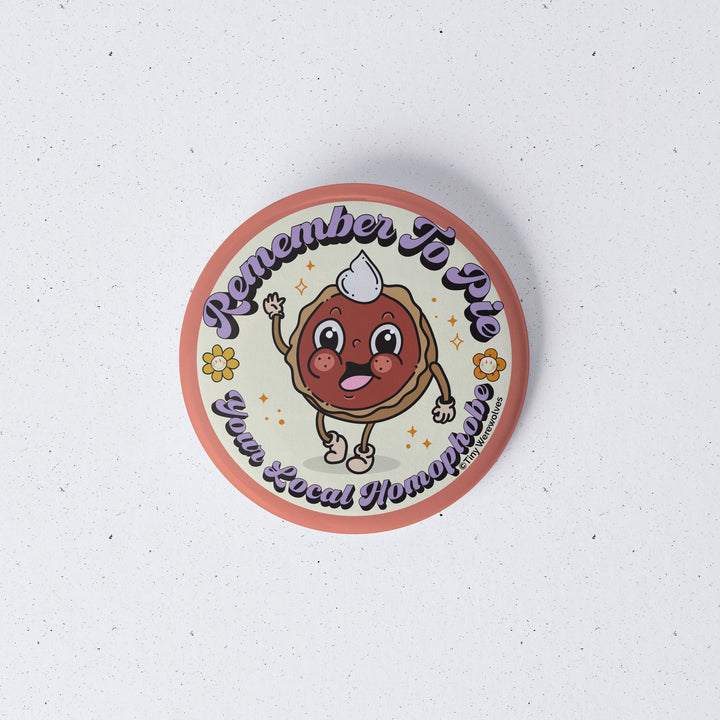 Based in Chicago by queer artist & designer Kayla Pekkala - Tiny Werewolves | Pie Your Local Homophobe 1" Mini Button Pin in | Shop to get your Metal Pinback Button with collections featuring retro-inspired designs infused with social commentary art, highlighting modern social & current events.