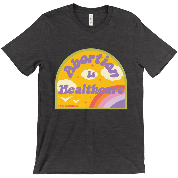 Based in Chicago by queer artist & designer Kayla Pekkala - Tiny Werewolves | Abortion is Healthcare Tee in Dark Heather Grey | Shop to get your Tee with collections featuring retro-inspired designs infused with social commentary art, highlighting modern social & current events.