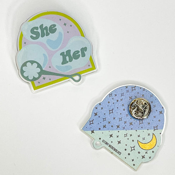 Based in Chicago by queer artist & designer Kayla Pekkala - Tiny Werewolves | She / Her Pronouns Bubble Acrylic Pin in Clear | Shop to get your Acrylic Pin with collections featuring retro-inspired designs infused with social commentary art, highlighting modern social & current events.